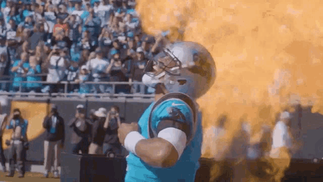 a man in a carolina panthers uniform stands in front of a fireball
