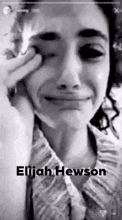 a woman is crying in a black and white photo with the name elijah hewson on the bottom .