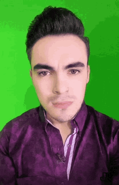 a man in a purple shirt is looking at the camera