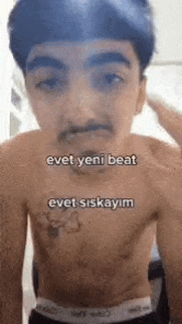 a shirtless young man with a mustache is standing in front of a mirror .