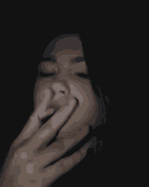 a woman is smoking a cigarette in the dark with a ring on her finger .