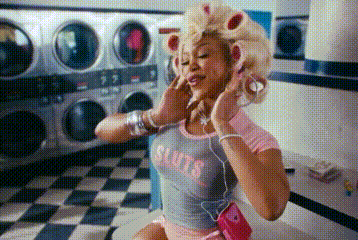 a woman with curlers in her hair is listening to music in a laundromat while wearing headphones .