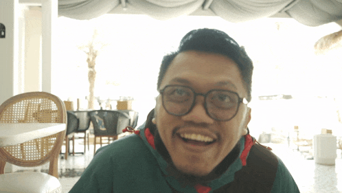 a man with glasses and a green jacket is smiling