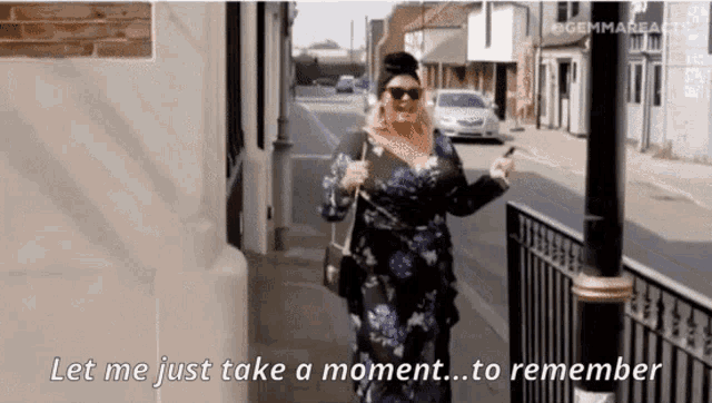a woman in a blue dress is walking down a street and says let me just take a moment to remember