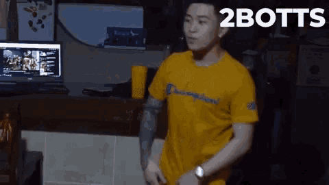 a man wearing a yellow champion shirt is standing in front of a computer screen