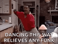 a man is dancing in a living room in a red shirt .