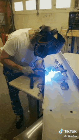 a man is welding a piece of metal in a garage .
