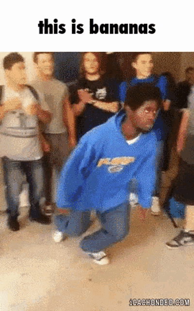 a man in a blue sweatshirt is kneeling down in front of a group of people with the words " this is bananas " above him