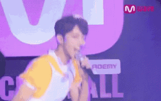a man is singing into a microphone in front of a sign that says academy .