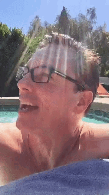 a man wearing glasses is laying in a pool with his mouth open
