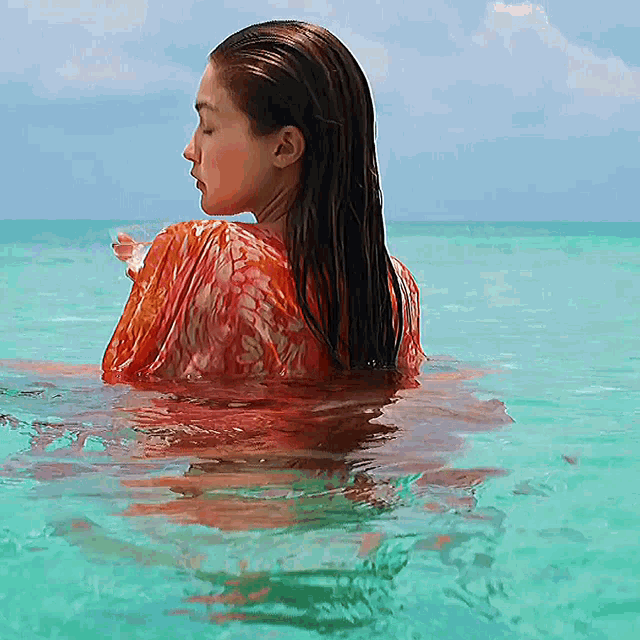 a woman in a red top is swimming in the ocean