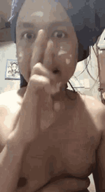 a shirtless man with a towel wrapped around his head is making a funny face .