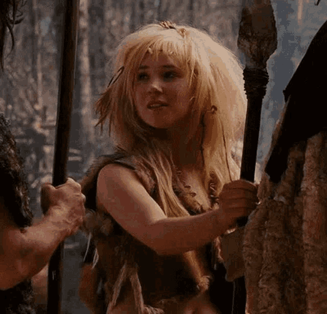 a woman in a fur coat is holding a spear in her hand .