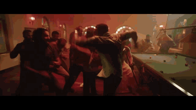 a group of people are dancing around a pool table
