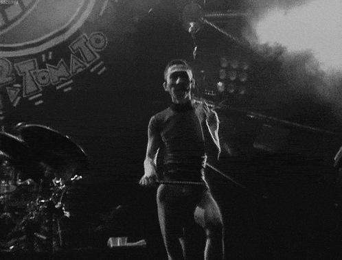 a black and white photo of a man on stage with the word tomato in the background