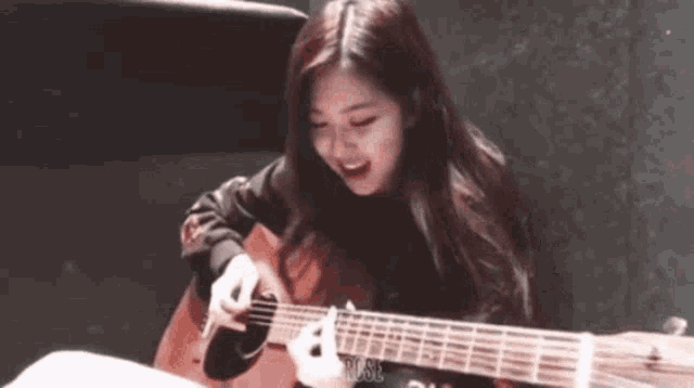 a young woman is playing a guitar in a dark room .