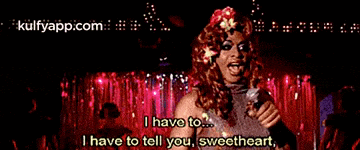 a drag queen is singing into a microphone and says i have to tell you sweetheart