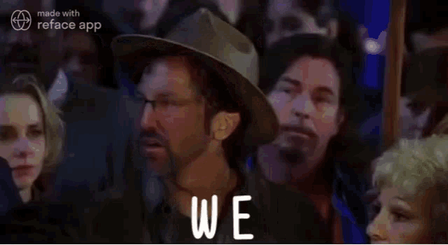 a group of people are sitting in a crowd and one of them is wearing a hat .