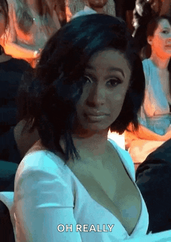 a woman in a white dress is sitting in a crowd of people .