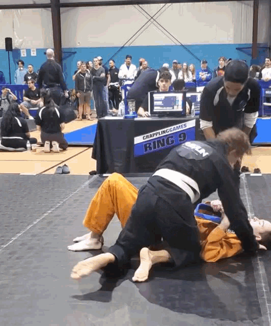 two people are wrestling in front of a table that says ring 9