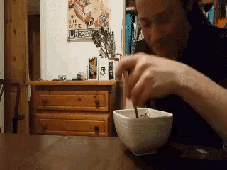 a man is eating cereal in front of a sign that says the life of the underdog
