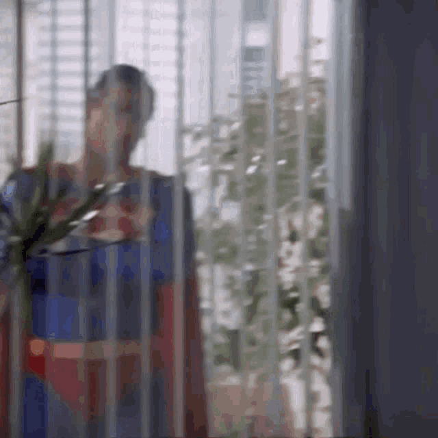 a man in a superman suit is standing in front of a window .