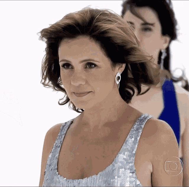 a woman wearing a silver sequined top and earrings stands in front of a white background