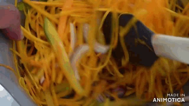 a person is stirring a salad with a spoon in a bowl .