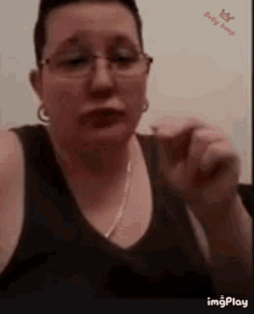a woman wearing glasses and a black tank top is giving a thumbs up
