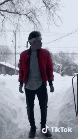 a man wearing a red jacket is standing in the snow with a tiktok watermark on the bottom
