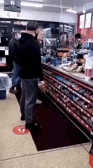 a man is standing in a convenience store holding a drink .