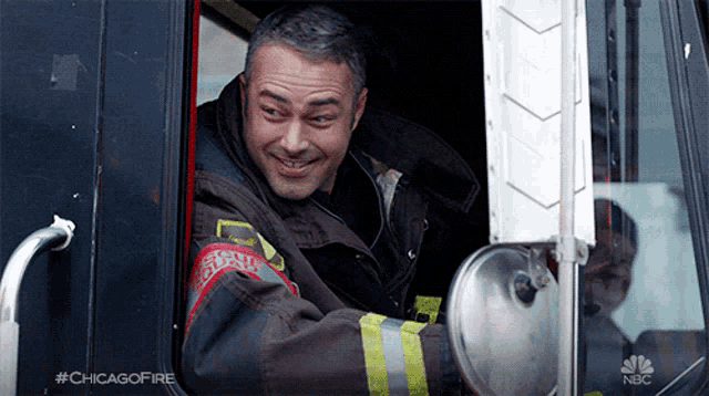 a man in a chicago fire uniform is smiling while sitting in a truck