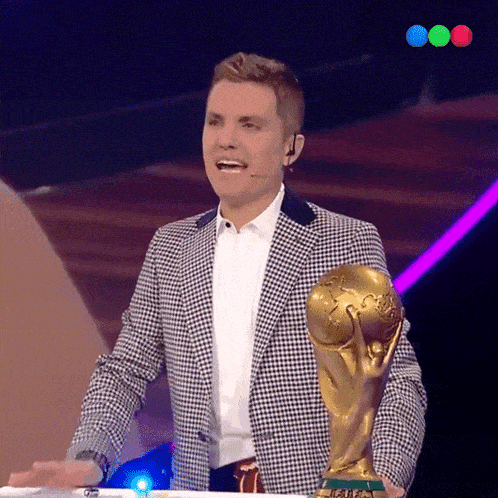 a man in a plaid jacket is holding a trophy that says fifa