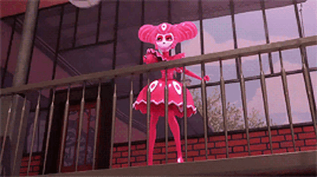 a pink doll is standing on a balcony with a brick building in the background
