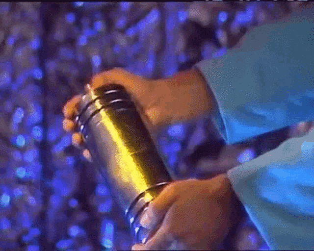 a person wearing a blue shirt is holding a gold object