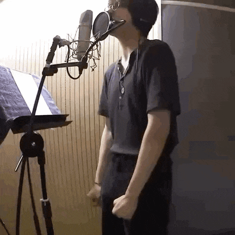 a man is singing into a microphone in a recording studio while wearing headphones .