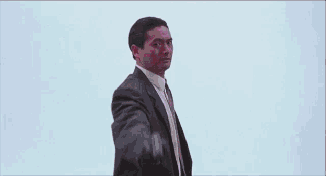 a man in a suit and tie is pointing a gun at a bloody background