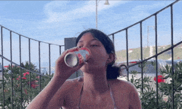 a woman in a bikini is drinking from a can that says ' coca cola ' on it