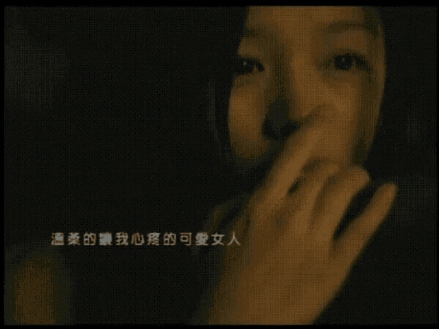 a woman covering her mouth with her hand in a dark room