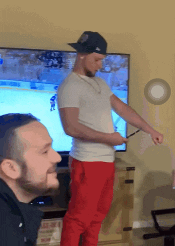 a man in red pants is standing in front of a television