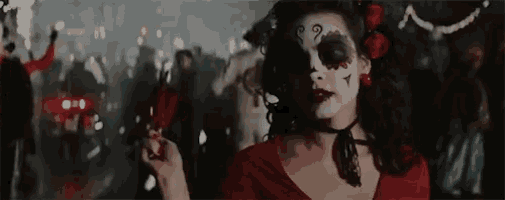 a woman in a day of the dead costume is holding a feather