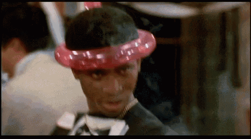 a man wearing a pink balloon hat and a tuxedo