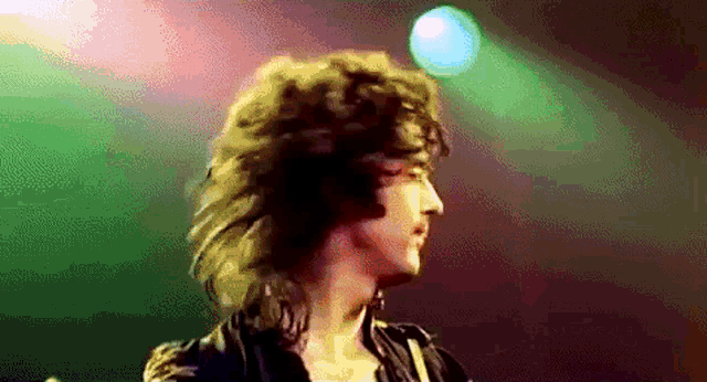 a man with long curly hair is standing in front of a stage
