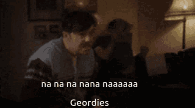 a man sitting in a dark room with the words na na na nana naaaa geordies written on the bottom