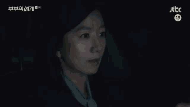 a woman is sitting in a car in the dark looking at something .