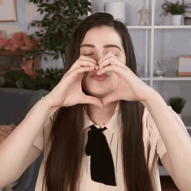 a woman with long hair is making a heart with her hands