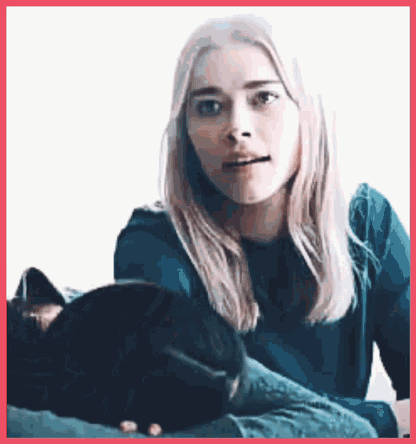 a woman is holding a black cat on her lap .