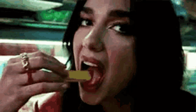 a woman is eating a french fry with her tongue hanging out .