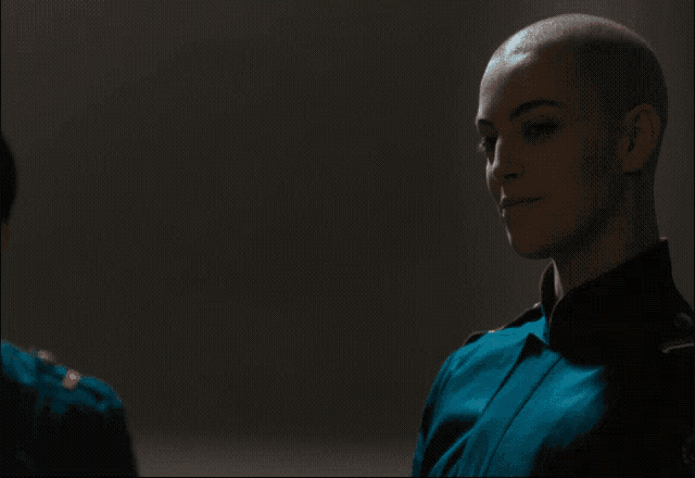 a woman with a shaved head is wearing a blue uniform