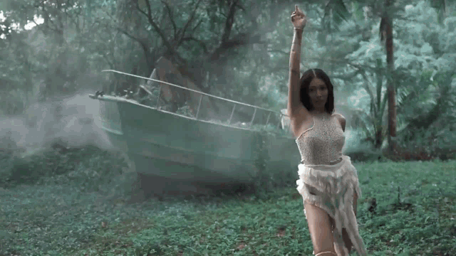 a woman in a white lace dress is standing in a foggy forest .